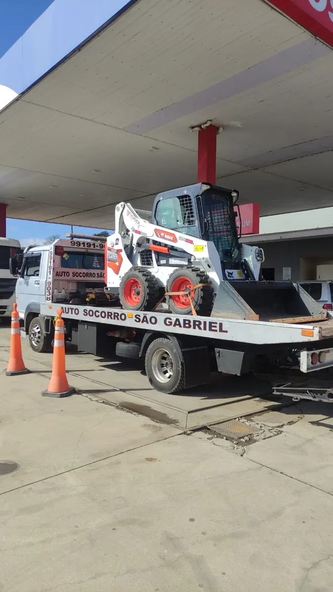 Máquina agrícola compacta sendo transportada na plataforma do guincho